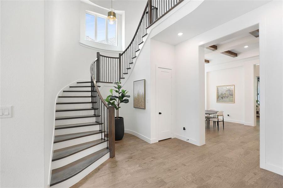 Grand entryway featuring a curved staircase with dark risers and light wood treads, black metal balusters, and a light wood handrail