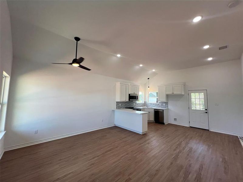 Kitchen with stainless steel appliances, ceiling fan, lofted ceiling, kitchen peninsula, and dark wood-type flooring