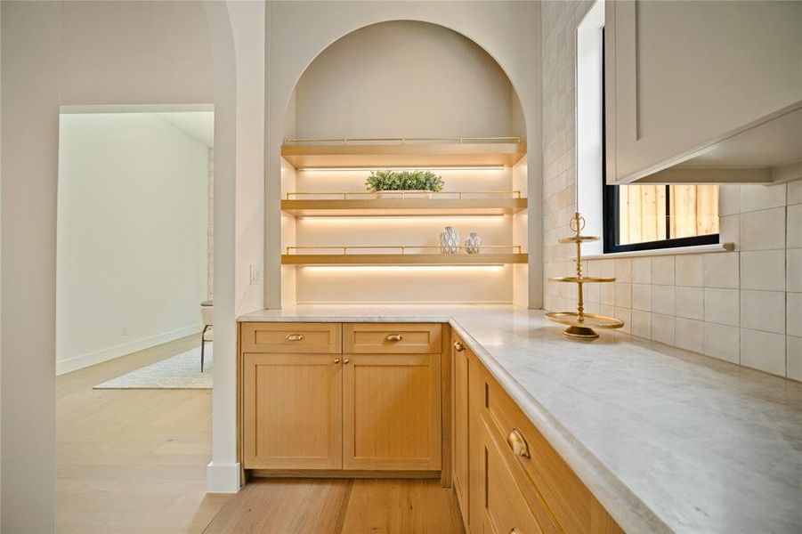 Kitchen featuring light countertops, tasteful backsplash, light wood-style floors, and open shelves