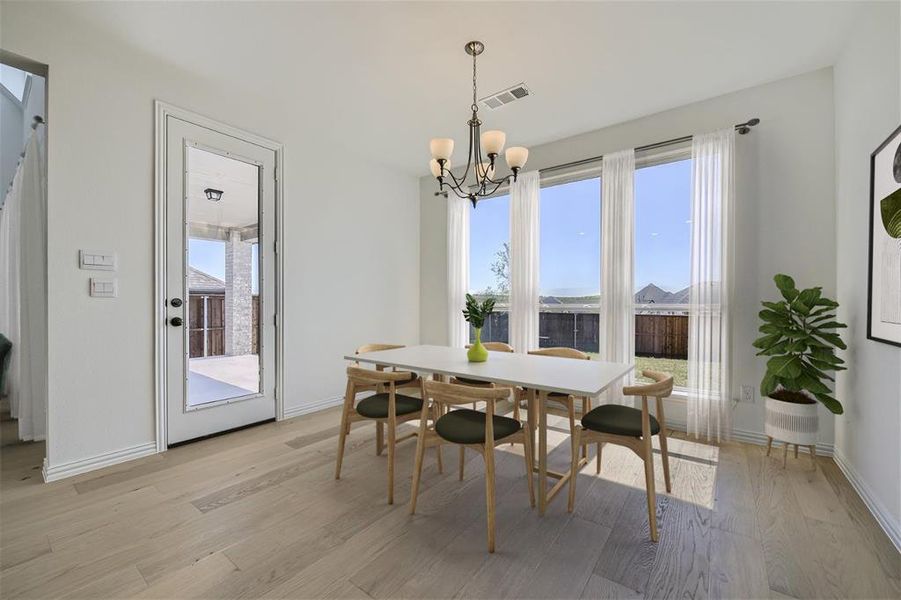 Virtually Staged Photo - Dining room with a chandelier and light wood-type flooring