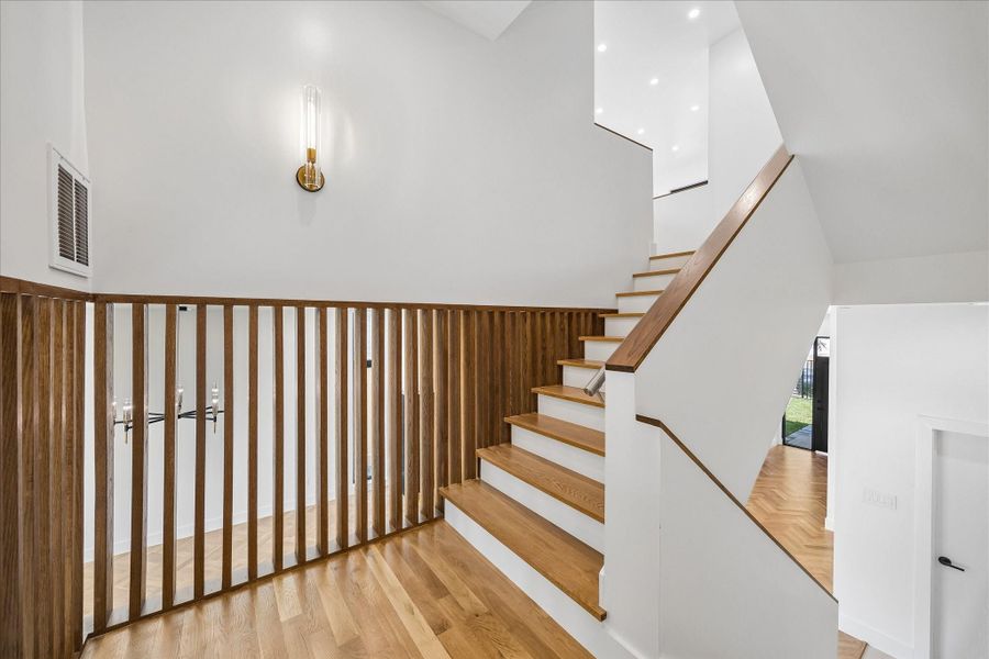 A modern staircase with elegant wood accents and sleek white walls, featuring contemporary lighting and an open design. A modern staircase with elegant wood accents and sleek white walls, featuring contemporary lighting and an open design.