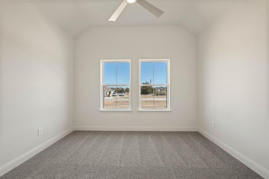 Unfurnished room with lofted ceiling, ceiling fan, carpet floors, and baseboards