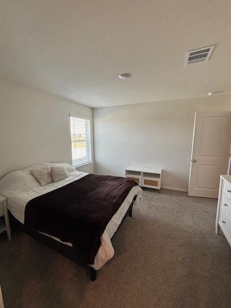 Carpeted room featuring a single window with blinds, a ceiling-mounted light fixture, and a white interior door