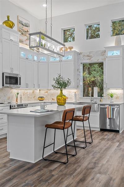 Kitchen featuring white cabinetry, a kitchen island, dark hardwood / wood-style flooring, stainless steel appliances, and decorative light fixtures