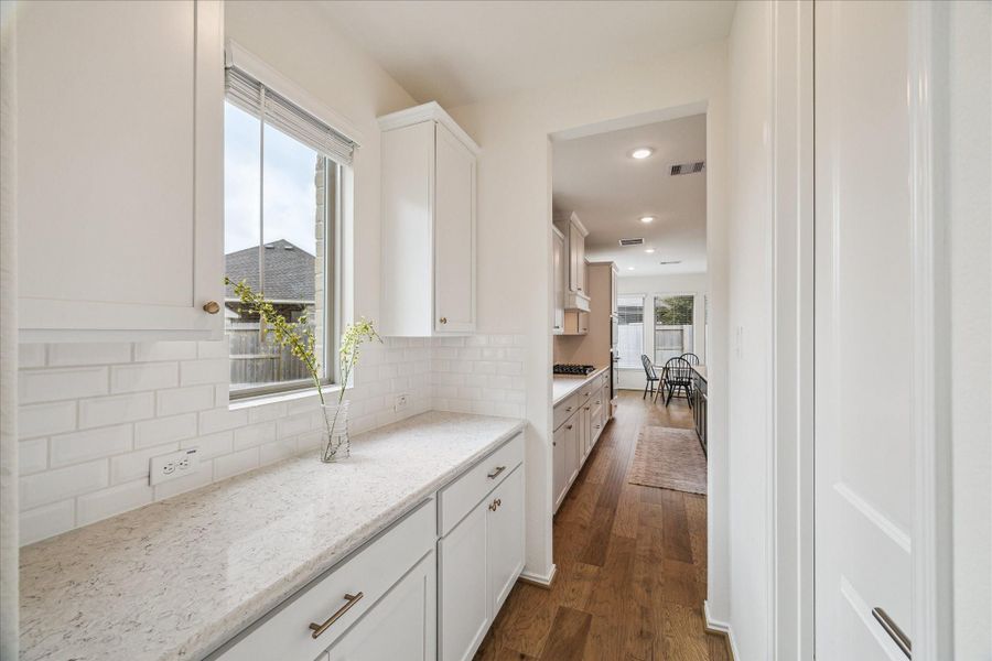 The bright butler’s pantry, situated between the formal dining room and kitchen, features ample countertop space, a charming bay window with side yard views, and a walk-in pantry opposite.