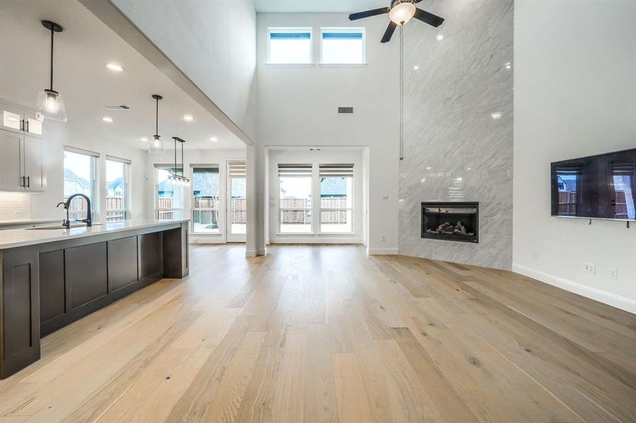 Kitchen with open floor plan, light countertops, a fireplace, light wood-style floors, and hanging light fixtures