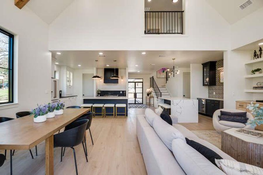 Living area featuring light wood-style flooring, high vaulted ceiling, stairway, recessed lighting, and beamed ceiling