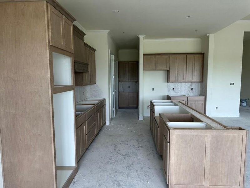 Kitchen featuring light wood-finish cabinetry, a central island, and white walls with crown molding