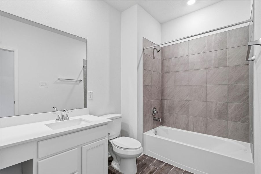 Well-appointed secondary bath with tub/shower combination and tile surround. It also features an extended vanity with a light countertop and a mirror that extends the full length of the vanity. Well-appointed secondary bath with tub/shower combination and tile surround. It also features an extended vanity with a light countertop and a mirror that extends the full length of the vanity.