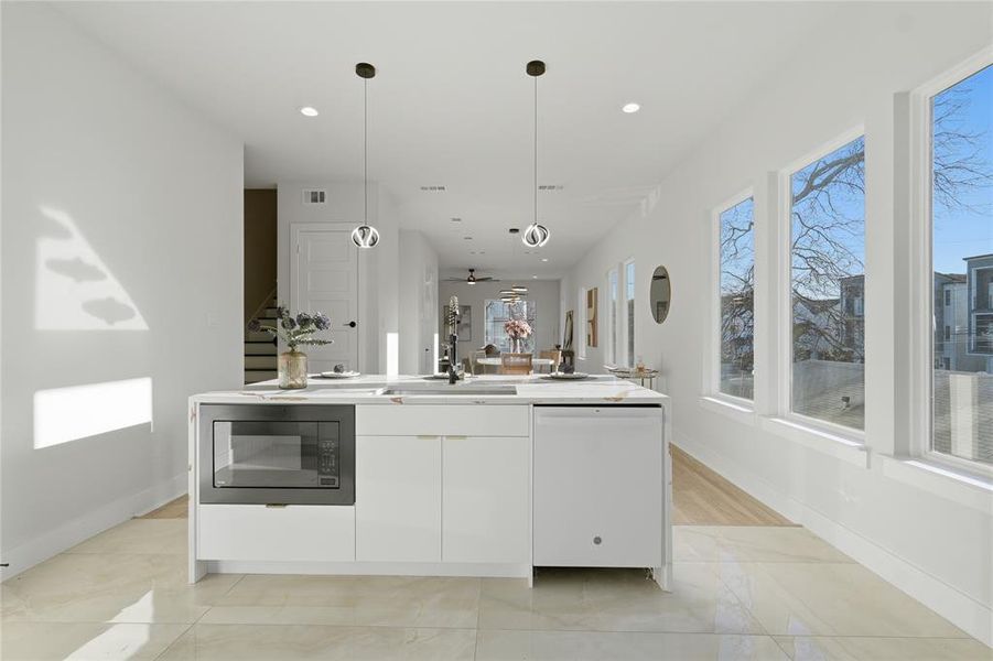 Kitchen with black microwave, dishwasher, a kitchen island with sink, modern cabinets, and white cabinets Kitchen with black microwave, dishwasher, a kitchen island with sink, modern cabinets, and white cabinets