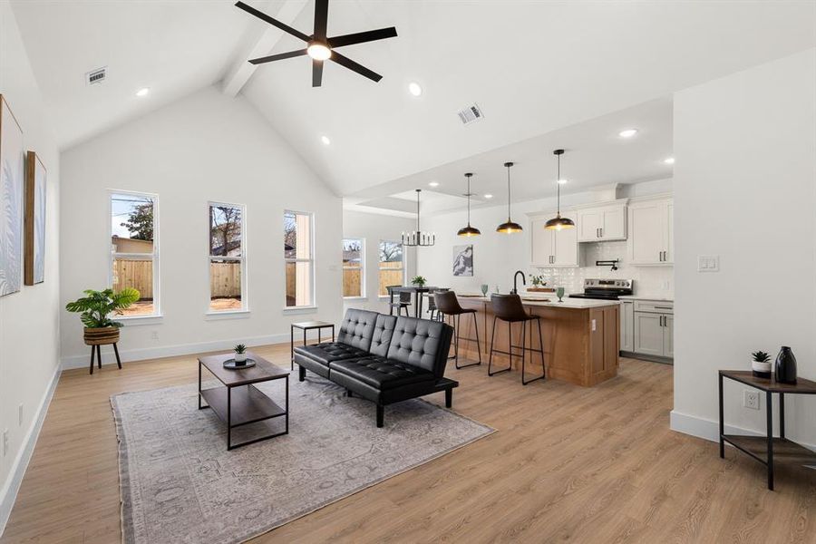 Living area with high vaulted ceiling, beam ceiling, visible vents, and light wood-style floors