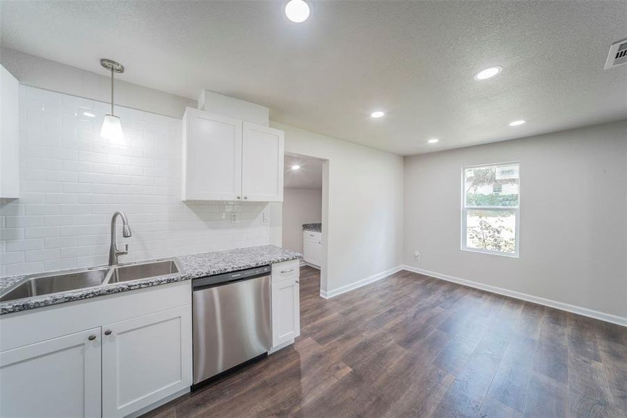 Kitchen featuring dark hardwood / wood-style floors, tasteful backsplash, dishwasher, sink, and white cabinetry