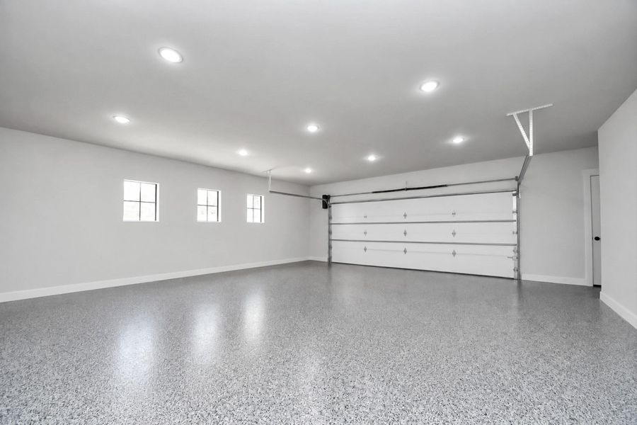 Spacious garage with polished floors, ample lighting, and a large, modern door for easy access.