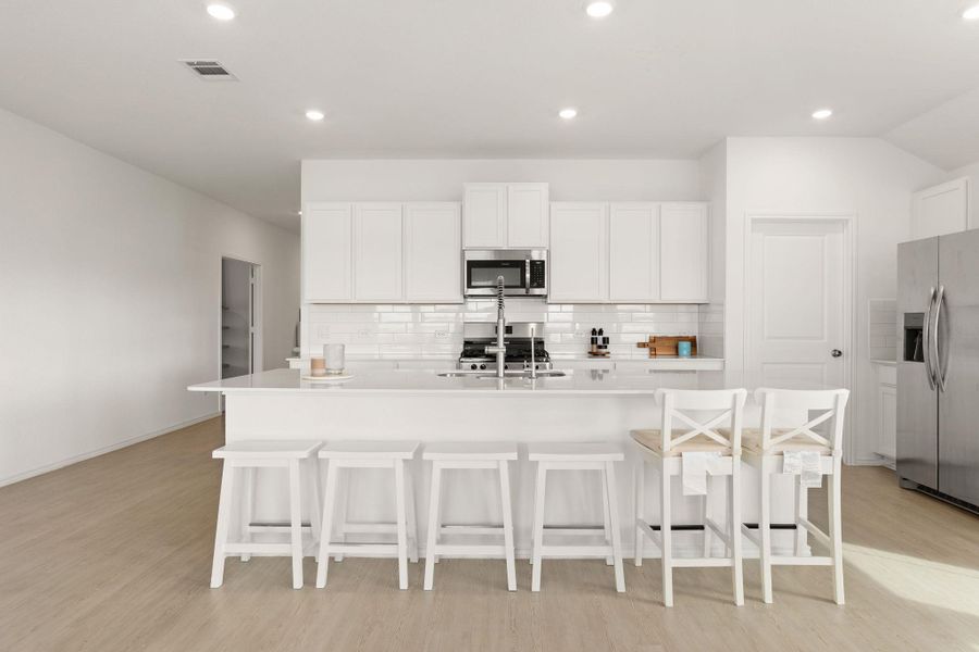 A pristine culinary space features an inviting island, crisp white cabinetry, and durable flooring, ideal for entertaining.