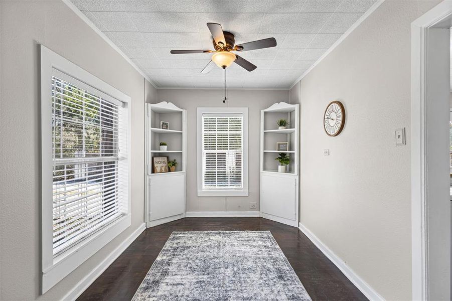Doorway with ceiling fan, wood finished floors, crown molding, and built in shelves