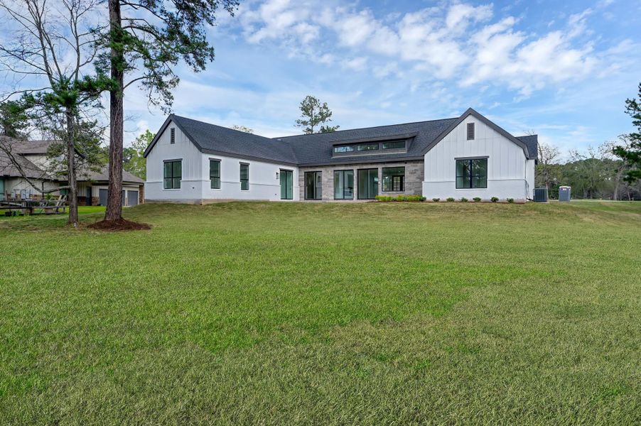 Full rear elevation showcasing the home’s modern farmhouse design, large windows, and seamless indoor-outdoor living spaces.