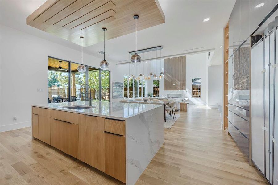 Kitchen featuring modern cabinets, light wood finished floors, light stone counters, decorative light fixtures, and recessed lighting Kitchen featuring modern cabinets, light wood finished floors, light stone counters, decorative light fixtures, and recessed lighting