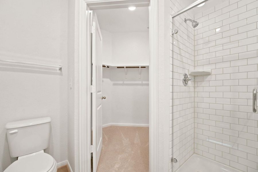 Crisp subway tile lines the modern walk-in shower adjacent to a spacious closet.