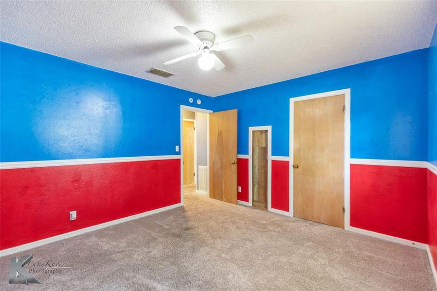 Unfurnished bedroom with a textured ceiling, carpet flooring, and a ceiling fan