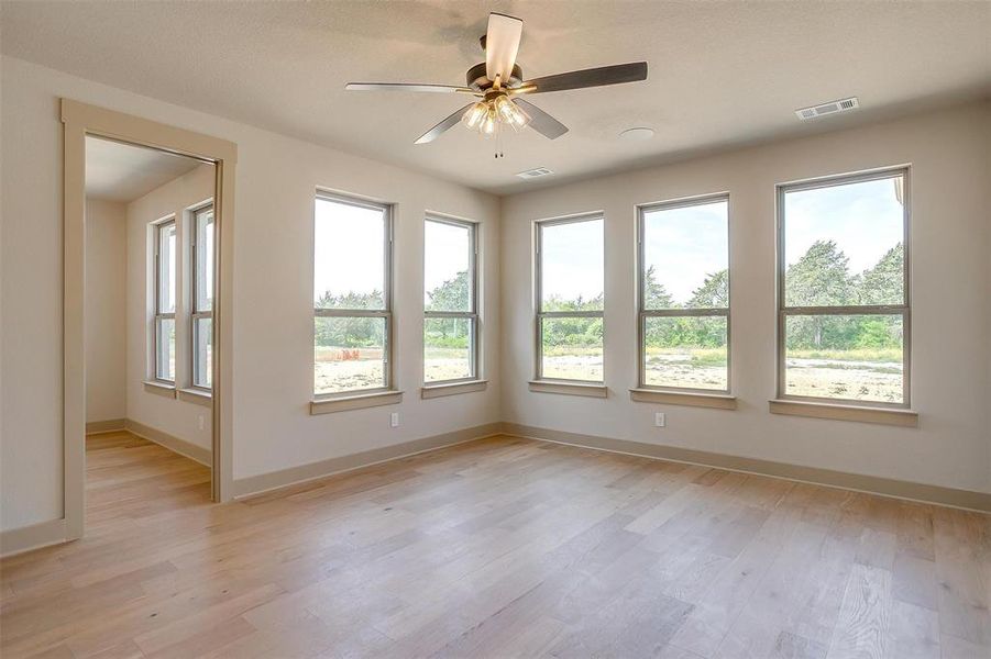 Unfurnished room featuring baseboards, visible vents, a ceiling fan, and light wood finished floors