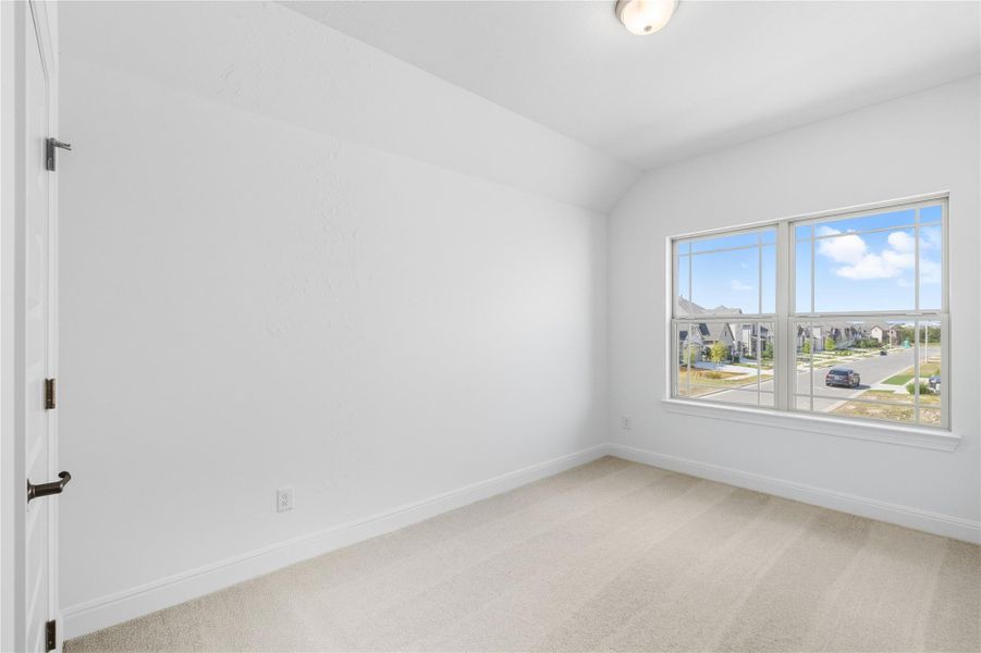 Empty room featuring light carpet and lofted ceiling