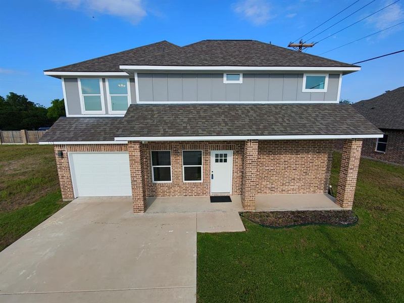 View of front of house featuring a garage, a front yard, roof with shingles, and brick siding View of front of house featuring a garage, a front yard, roof with shingles, and brick siding