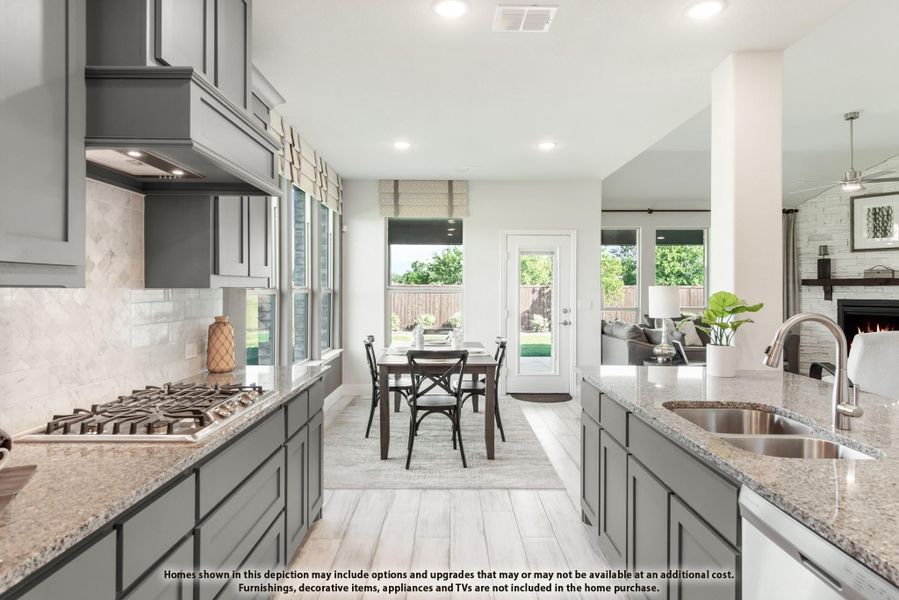Kitchen with gray cabinets, granite countertops, gas cooktop, and open view to dining area and living room with fireplace.