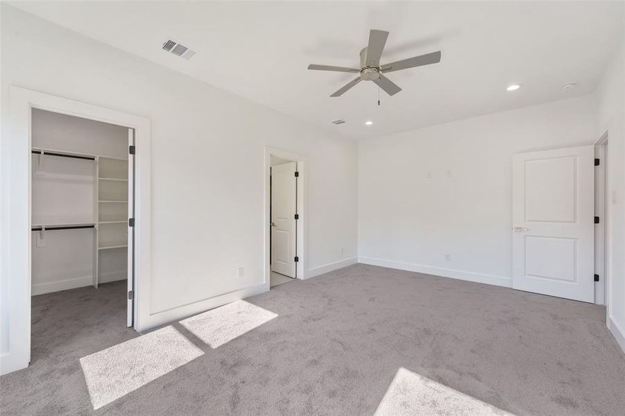 Unfurnished bedroom featuring light colored carpet, recessed lighting, a walk in closet, and ceiling fan