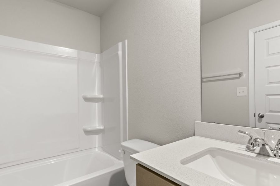Image of a bathroom with a white vanity, a large mirror, a white vinyl shower and tub, and light grey painted walls