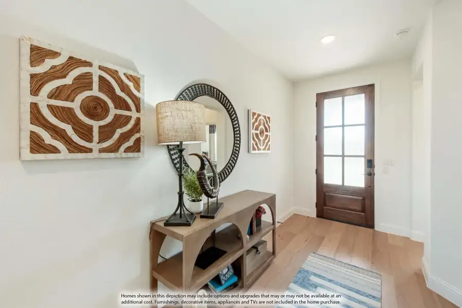 Entryway with wood console table, round mirror, wall art, and wood front door with glass panels on light hardwood floors