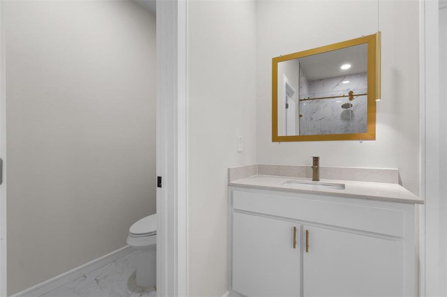 Bathroom featuring a white vanity with a light countertop, a gold-framed mirror, and a bronze-finish faucet