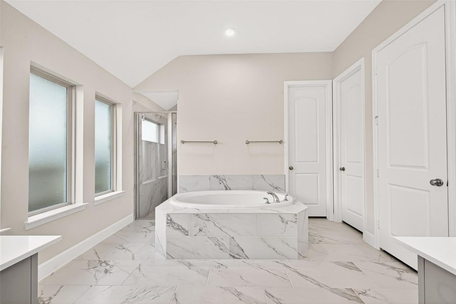 Luxurious primary en-suite bath featuring elegant double-door entry, an upgraded Jacuzzi soaking tub, and a walk-in rain shower with frosted glass accents. Complete with a double vanity, upgraded medicine cabinets, and separate his-and-hers walk-in closets with built-in shelving, this spa-inspired retreat offers exceptional comfort and sophistication Luxurious primary en-suite bath featuring elegant double-door entry, an upgraded Jacuzzi soaking tub, and a walk-in rain shower with frosted glass accents. Complete with a double vanity, upgraded medicine cabinets, and separate his-and-hers walk-in closets with built-in shelving, this spa-inspired retreat offers exceptional comfort and sophistication