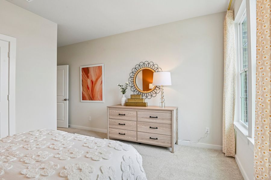 A bedroom with a mirror and dresser.