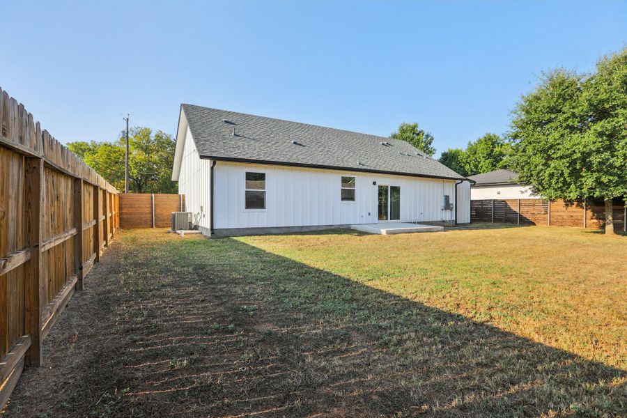 Back of property with a patio area, a fenced backyard, a shingled roof, and board and batten siding