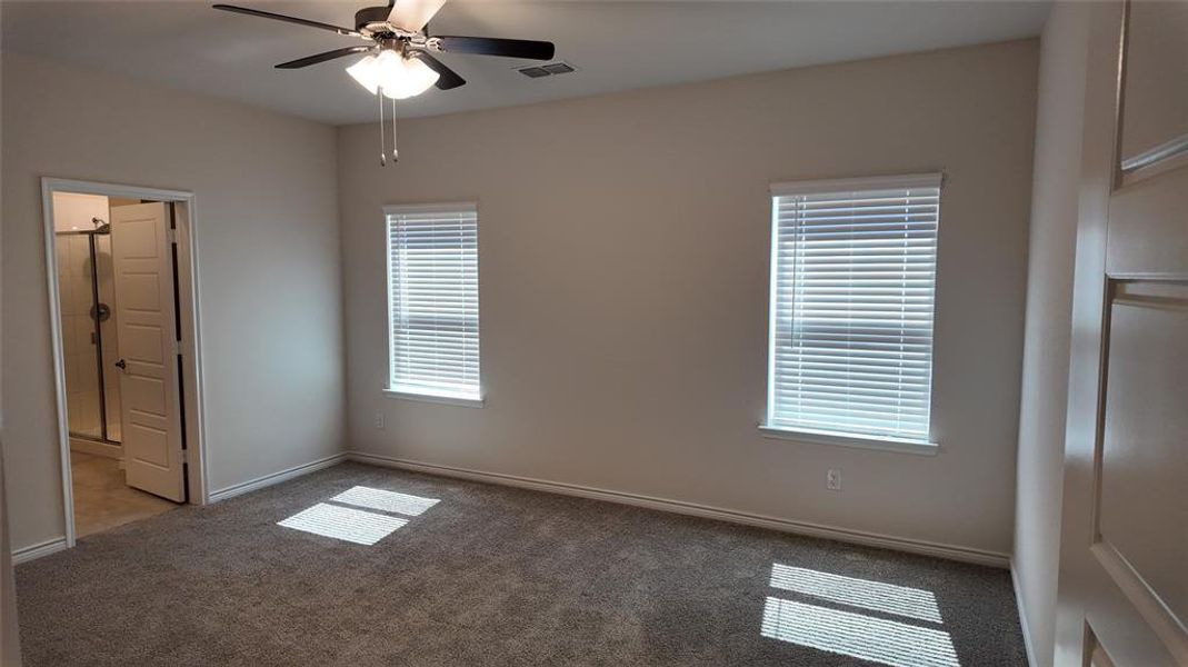 Unfurnished bedroom with carpet, connected bathroom, and a ceiling fan