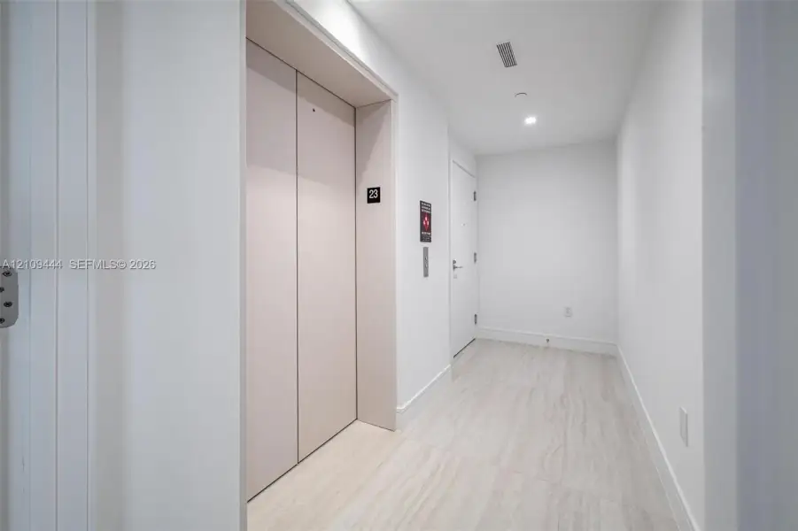 Private elevator access featuring matte-finish doors, recessed ceiling lighting, and large-format stone-look floor tiles