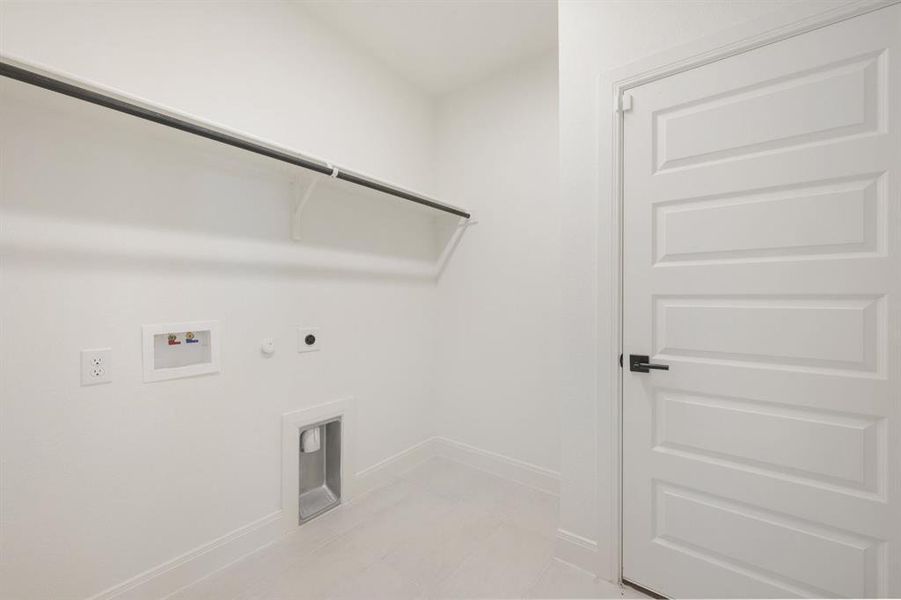 Dedicated utility space featuring a laundry hookup, wall-mounted outlets, and an overhead shelf with a hanging rod