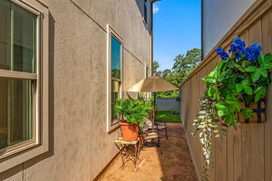 This charming side yard is the perfect setup for a bistro table and potted plants.