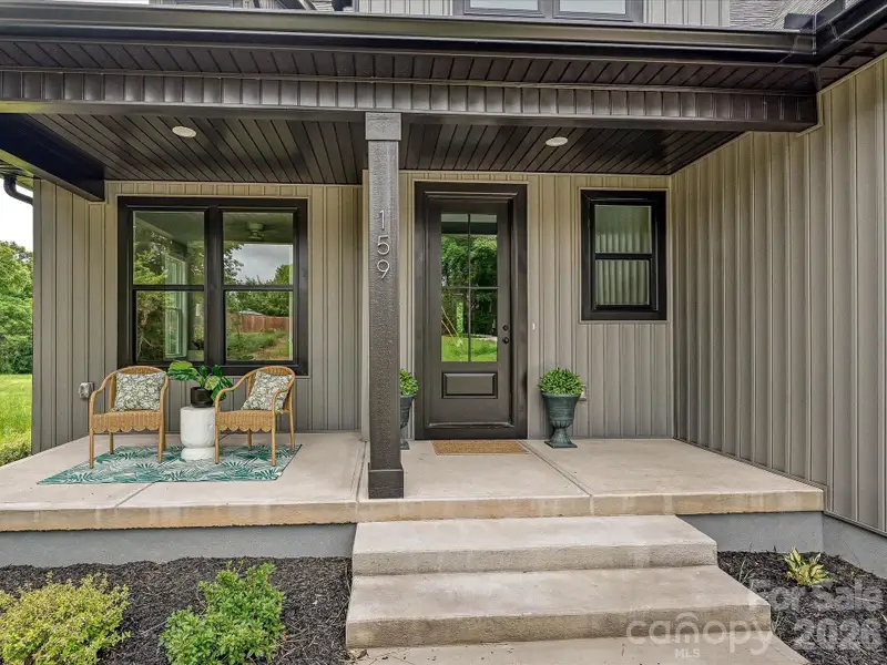 Charming covered front porch welcomes you with modern finishes, stylish seating, and the perfect space to relax and enjoy the peaceful surroundings.