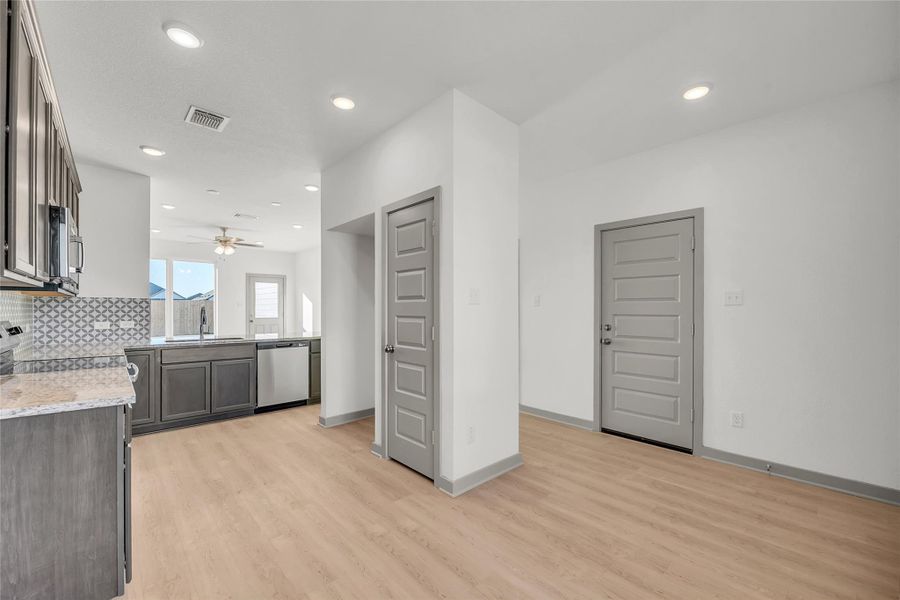 Kitchen featuring light stone countertops, stainless steel appliances, light wood finished floors, recessed lighting, and backsplash