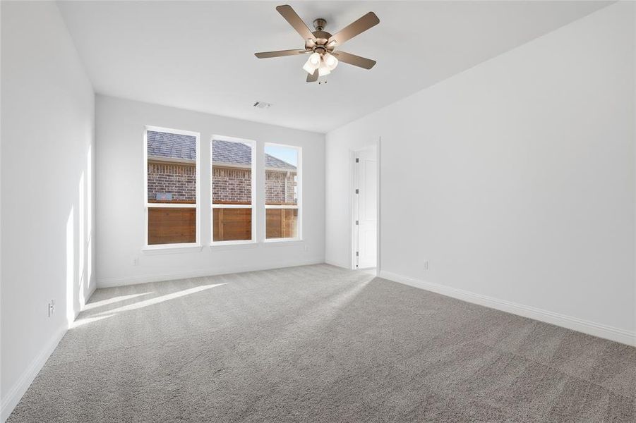 Carpeted empty room featuring baseboards and a ceiling fan