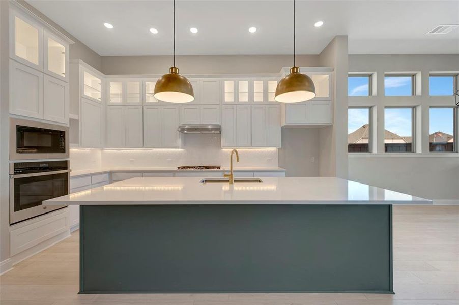 Two tone kitchen with oven, a kitchen island with sink, glass insert cabinets, pendant lighting, and two tone color scheme Two tone kitchen with oven, a kitchen island with sink, glass insert cabinets, pendant lighting, and two tone color scheme