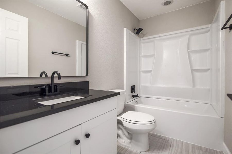 The full secondary/guest bathroom offers a contemporary vanity with quartz countertop, stylish finishes, designer tile floors, and a shower/tub combo.