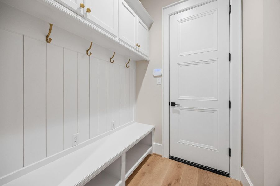 Mud Room sits at the interior garage entrance w/ golden coat hooks & shoe cubbies.