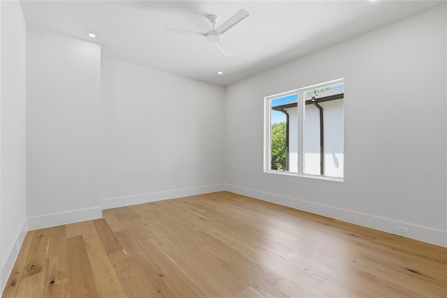 Secondary bedroom with hardwood floors, ceiling fan, and backyard-facing window Secondary bedroom with hardwood floors, ceiling fan, and backyard-facing window