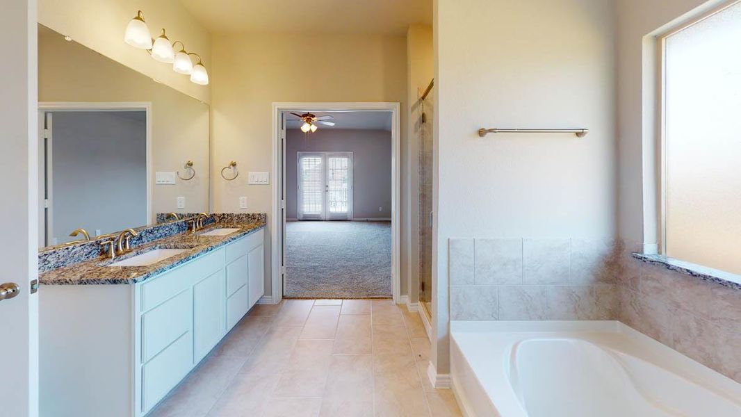 Bathroom featuring a garden tub, double vanity, ceiling fan, light tile patterned floors, and light carpet Bathroom featuring a garden tub, double vanity, ceiling fan, light tile patterned floors, and light carpet