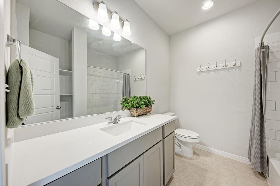 Bathroom with vanity, shower / bathtub combination with curtain, light tile patterned floors, and recessed lighting