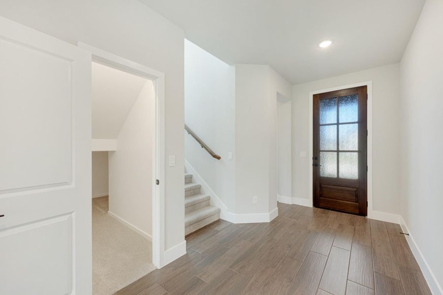 Home entryway with wood-look tile floors, dark wood front door with glass panels, and staircase with carpet treads Home entryway with wood-look tile floors, dark wood front door with glass panels, and staircase with carpet treads