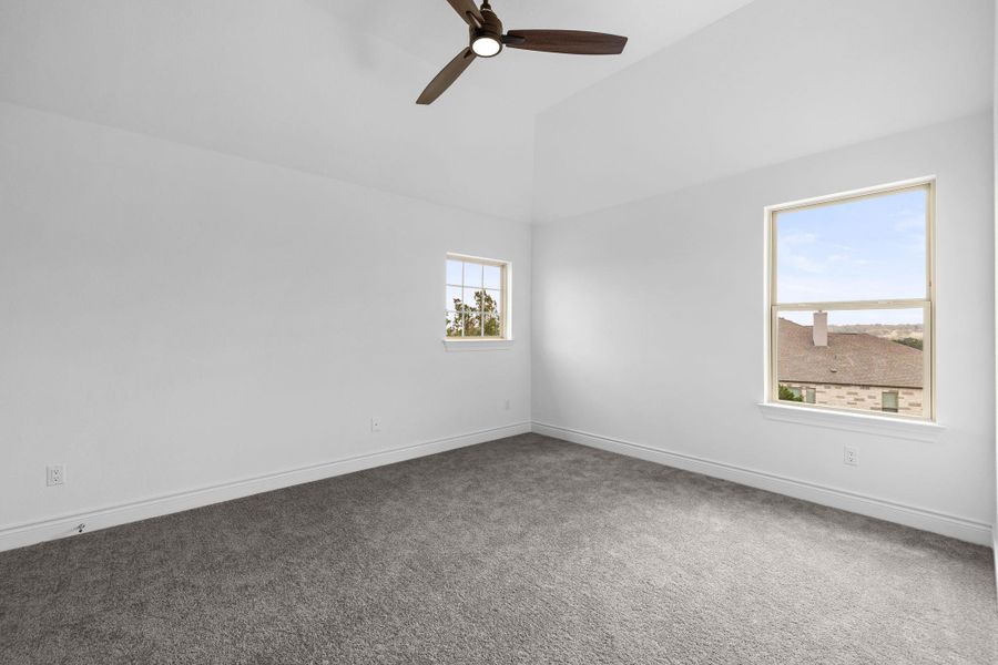 Carpeted empty room featuring a ceiling fan and high vaulted ceiling