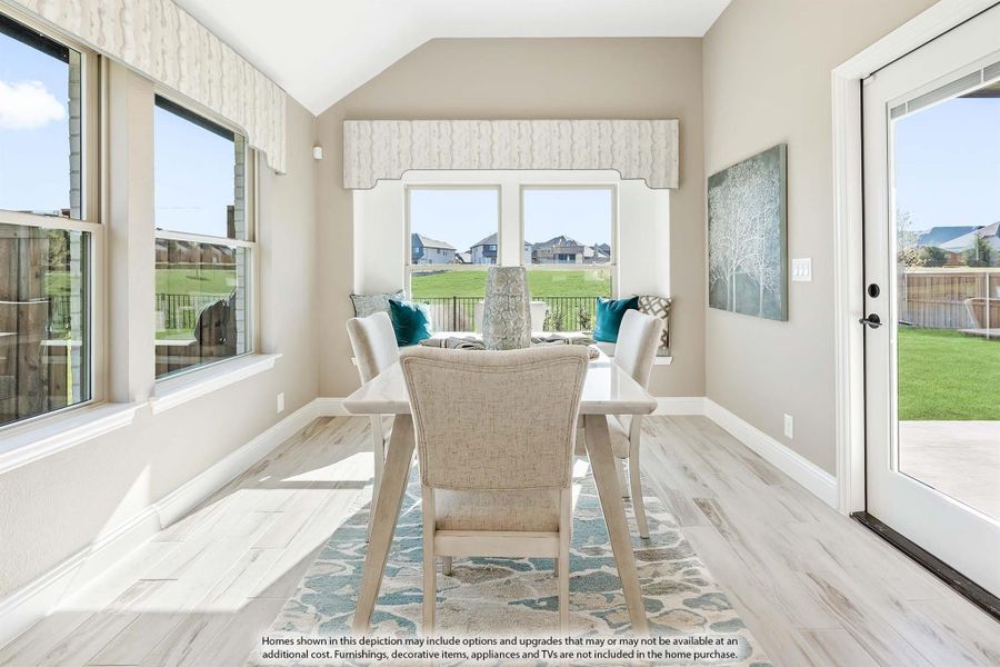 Bright dining area with vaulted ceiling, large windows, light wood floors, and patio door overlooking backyard Bright dining area with vaulted ceiling, large windows, light wood floors, and patio door overlooking backyard